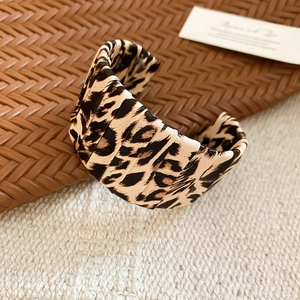 Macro detail of leopard print open cuff bracelet featuring unique accordion pleat textures