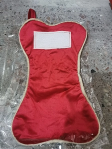 Detail of red satin Christmas stocking with gold braided trim in clear packaging