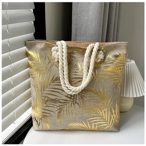 Detail of linen tote bag with gold palm leaf pattern and thick rope handle in sunlight