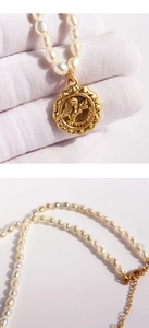 Macro detail of vintage freshwater pearl necklace with gold cupid angel pendant