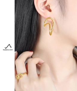 Detail view of model wearing gold-plated stainless steel curved earrings and a knot ring