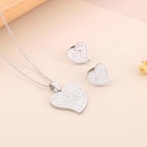 Close-up of heart-shaped necklace and earring set with shimmering crystal stones