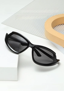 Close-up of black irregular sports sunglasses with dark lenses on a minimalist display