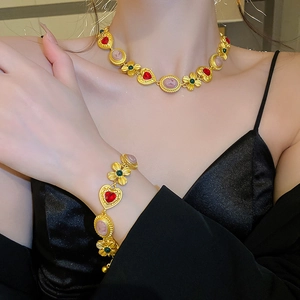 Detailed close-up of vintage gold necklace and bracelet set with heart gems and cameos