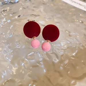 Detailed view of red and pink velvet textured double sphere earrings on water ripple background