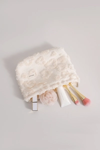 Macro detail of cream plush cosmetic bag with heart texture and H & K BAG label