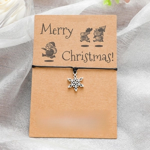 Handmade Christmas snowflake wish bracelet with black woven cord on brown kraft card