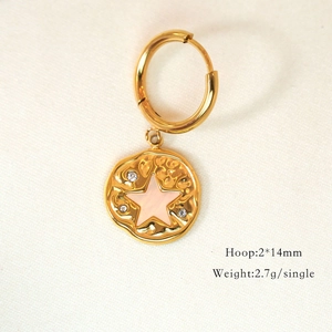 Macro shot of 14K gold hoop earrings with pink star pendant and sparkling crystals