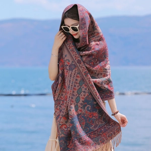 Ethnic style paisley scarf for women in reddish brown with fringes against an ocean backdrop