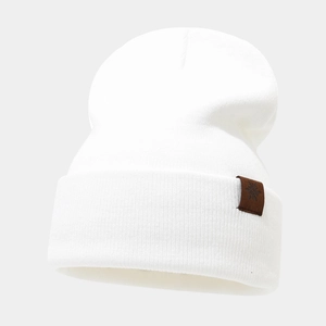 Close-up of white ribbed knit beanie featuring a brown leather patch with snowflake detail