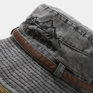 Dettaglio cappello da sole in tela lavata grigia con cinturino in pelle