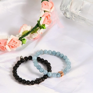 Matching magnetic couple bracelets with crown charms on elegant white satin background