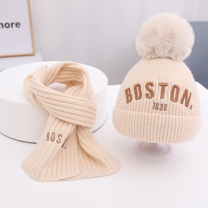Detail von cremefarbenem Strickmützen- und Schal-Set mit Boston 1630 Stickerei und Pelzbommel