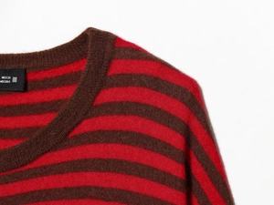 Gros plan sur l'encolure d'un pull rayé rouge et marron avec étiquette de taille