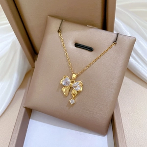 Close-up of golden bow pendant with zircon crystals on premium silk jewelry cushion