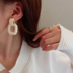 Vintage acrylic twisted geometric hoop earrings in cream white shown on a female model