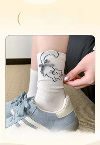 Detail of white cotton socks with cute cat pattern and black checkered bow ornament