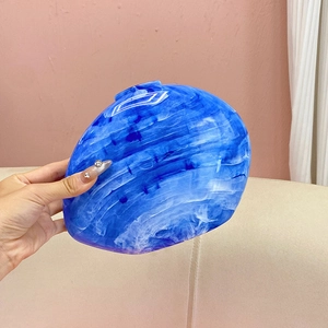 Close-up of a blue marble texture acrylic clutch bag held in hand for evening events