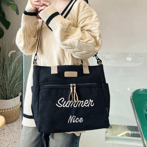 Detail showing Summer Nice embroidery and Hello Keke label on black canvas tote bag