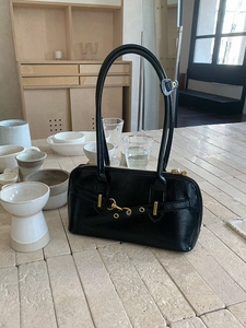 Detail of vintage black leather bowling bag showing golden metal buckle on stone table