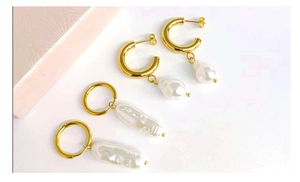 Detailed macro view of 18K gold-plated C-shaped earrings with baroque pearls on white backdrop