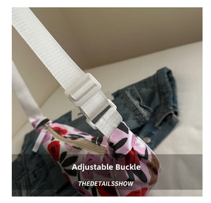 Detail of adjustable strap buckle on large floral hobo bag with denim background