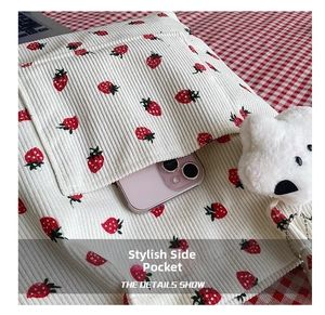 Detail of strawberry print corduroy tote showing side pocket used for smartphone storage