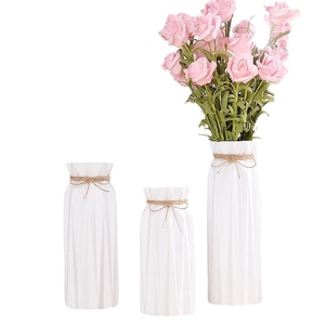 Three minimalist white ceramic vases with twine bows and textured finish with pink roses