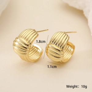Macro detail showing 1.8cm height and 1.1cm width of golden C-shaped textured earrings