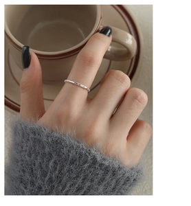 Close-up of slender silver ring featuring colorful small gemstones on a hand