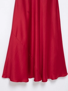 Gros plan sur le satin rouge montrant le drapé élégant et la texture brillante de la robe