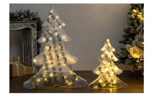 Detail of flocking snowy Christmas tree set with warm LED lights in festive indoor setting