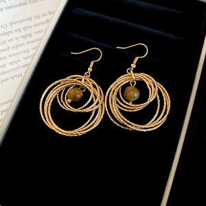 Detailed view of golden multi-layer circular drop earrings with brown tiger eye stone beads