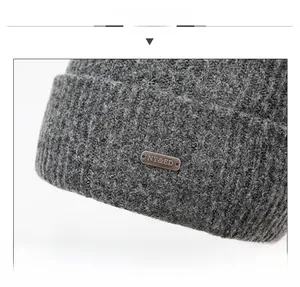 Detailed close-up of dark grey knitted beanie fabric with metallic brand tag