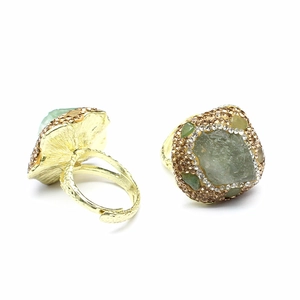 Detail view of gold adjustable rings featuring raw green amethyst stones with pave edges