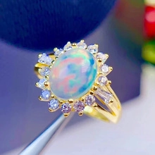 Macro detail of golden sunflower ring featuring oval opal center and zircon halo stones