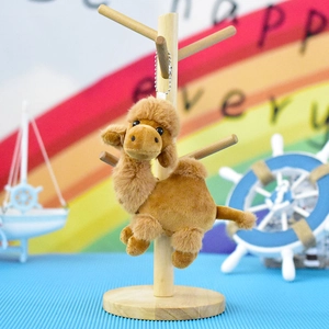 Detailed view of a cute brown plush camel keychain hanging on a wooden display stand