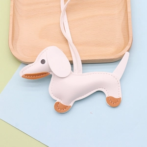 Detail of cream faux leather dachshund bag charm with brown accents and long lanyard