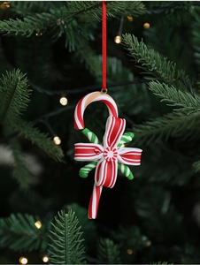 Detail of candy cane Christmas ornament with red bow and stripe patterns on a tree
