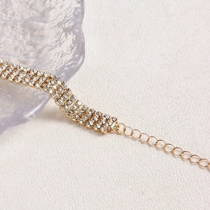 Detail of a three-row rhinestone choker with gold finish and adjustable chain links