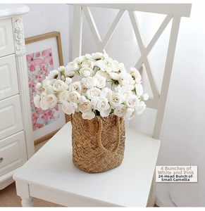 Close-up of white and pink camellia bouquets in a woven basket on a white wooden chair