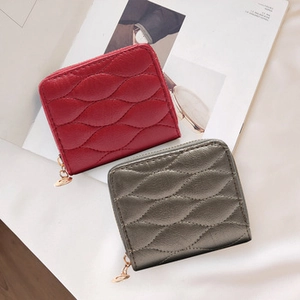 Close-up of quilted pattern and zipper detail on red and gray faux leather wallets