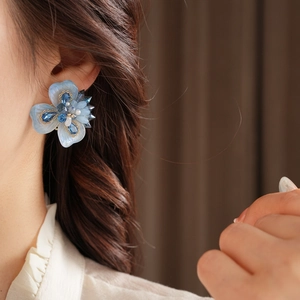 Gros plan de boucles d'oreilles fleurs bleues avec strass et perles sur un mannequin