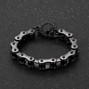 Detail of black stainless steel bike chain bracelet with matte finish on textured surface