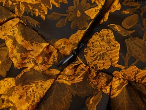 Close-up of black and gold jacquard fabric texture with a hidden zipper on a dress