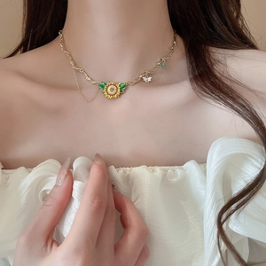 Detail of sunflower necklace with bee charm on textured gold chain worn by model