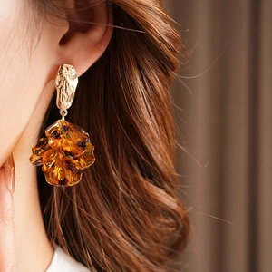 Detailed close-up of vintage golden petal tassel earring worn by a model in soft lighting