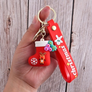Close-up of PVC Christmas keychain with red boot and reindeer charms on a wooden background
