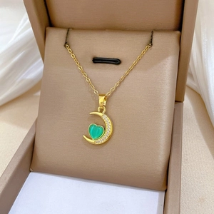 Detailed shot of crescent moon and green heart pendant necklace in luxury jewelry box