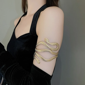 Détail d'un bracelet de bras serpent doré à double tête porté sur une manche en velours